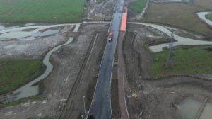 An aerial view of a road crossing a river and next to a construction site in Melton Mowbray
